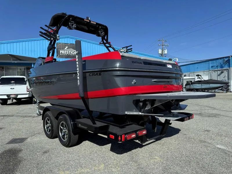 Slide: The Image of 2021 Moomba Craz boat on trailer, gray and red, parked outdoors near blue building. - 5