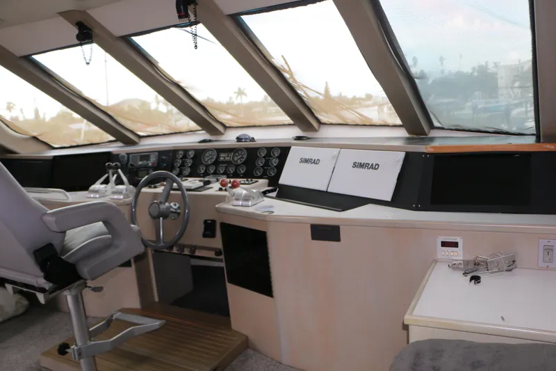 Slide: The Image of 1990 Donzi 65 yacht cockpit with steering wheel, control panels, and Simrad navigation systems. - 14
