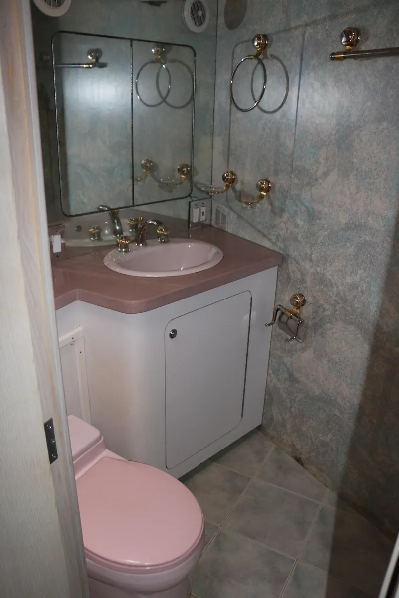 Slide: The Image of 1990 Donzi 65 yacht bathroom with pink fixtures and gold accents. - 22