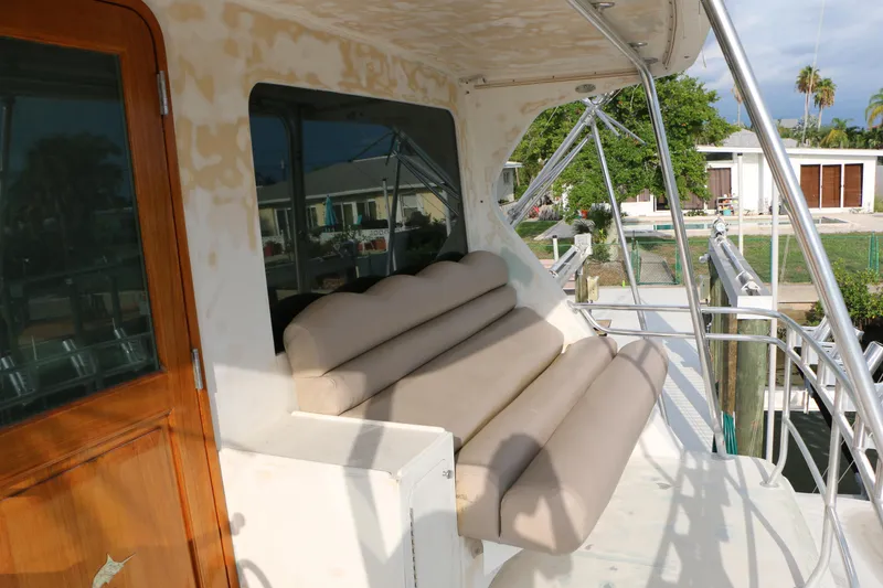 Slide: The Image of 1990 Donzi 65 yacht deck with cushioned seating and wooden door. - 4