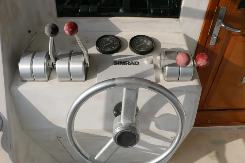 Slide: The Image of Control panel of a 1990 Donzi 65 boat with steering wheel and throttle levers. - 7