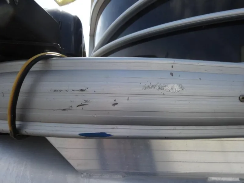 Slide: The Image of Close-up of a 2018 Sun Tracker 24XP3 pontoon boat with visible scratches on the aluminum siding. - 19