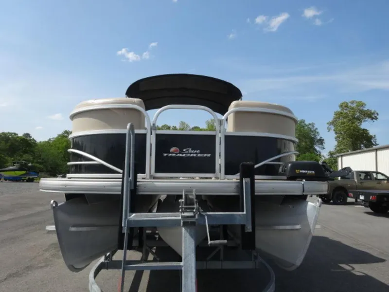 Slide: The Image of 2018 Sun Tracker 24XP3 pontoon boat on trailer, parked outdoors under blue sky. - 3