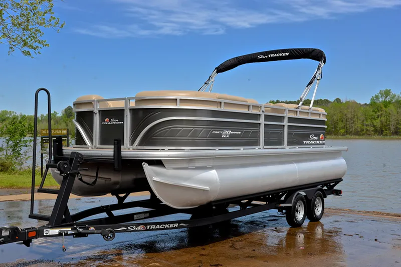 Slide: The Image of 2024 Sun Tracker Party Barge 20 DLX pontoon boat on trailer by a lake. - 10