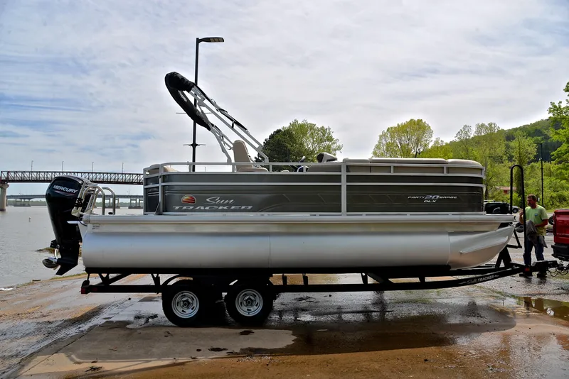 Slide: The Image of 2024 Sun Tracker Party Barge 20 DLX pontoon boat on trailer by a river. - 15