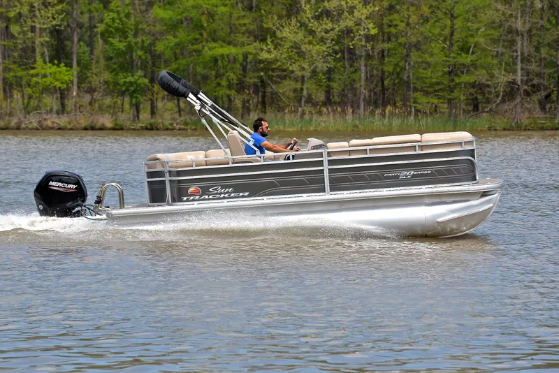 Slide: The Image of 2024 Sun Tracker Party Barge 20 DLX cruising on a lake with lush green trees. - 3