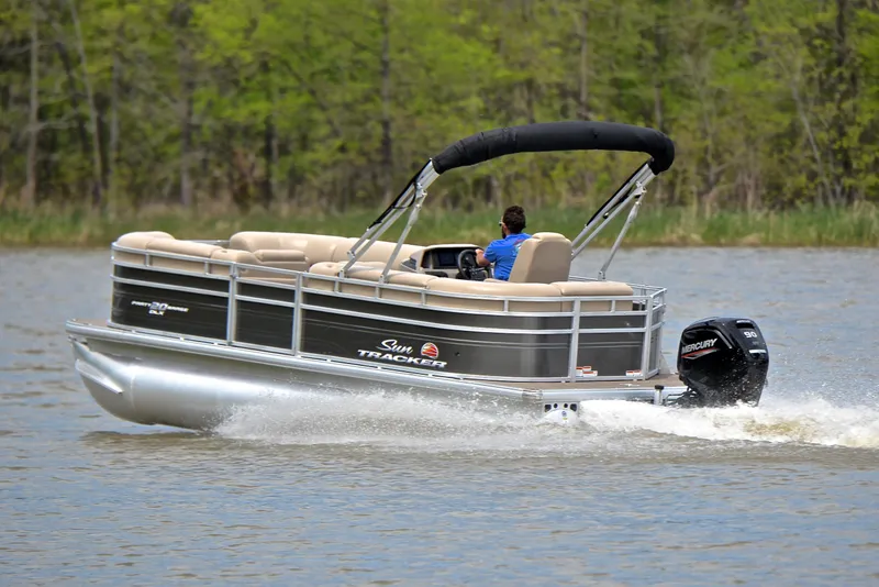 Slide: The Image of 2024 Sun Tracker Party Barge 20 DLX pontoon boat cruising on a lake. - 4