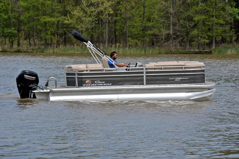 Slide: The Image of 2024 Sun Tracker Party Barge 20 DLX pontoon boat cruising on a calm lake. - 6