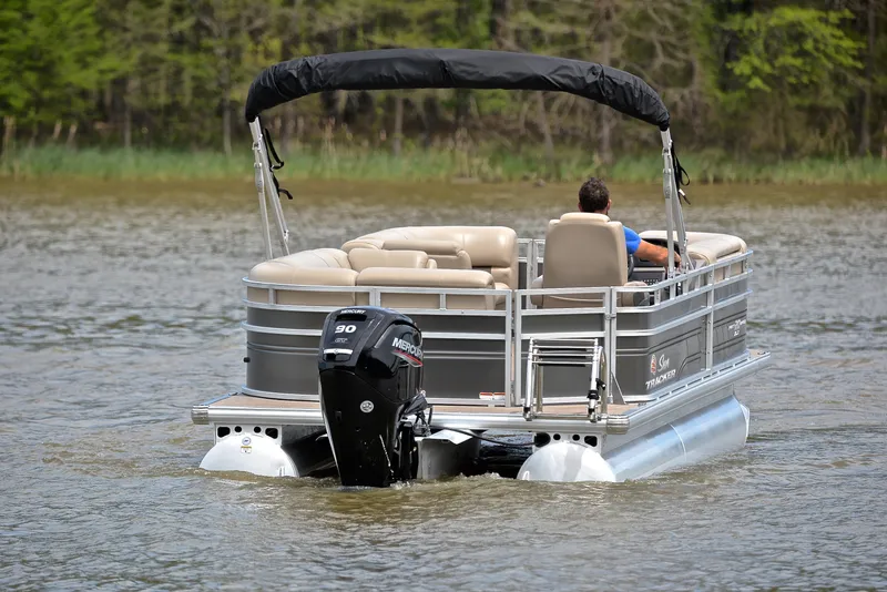 Slide: The Image of 2024 Sun Tracker Party Barge 20 DLX pontoon boat cruising on a calm lake. - 7