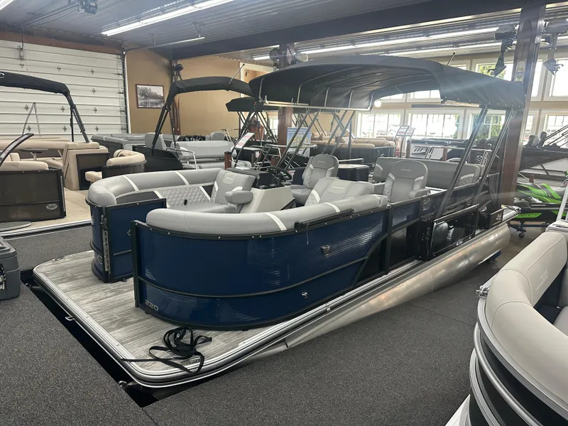 The Image of 2025 Crest Classic 220 pontoon boat with blue exterior and spacious seating, displayed indoors. - 1