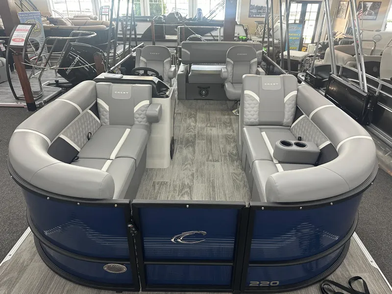 Slide: The Image of 2025 Crest Classic 220 pontoon boat with spacious seating and modern design in showroom. - 2
