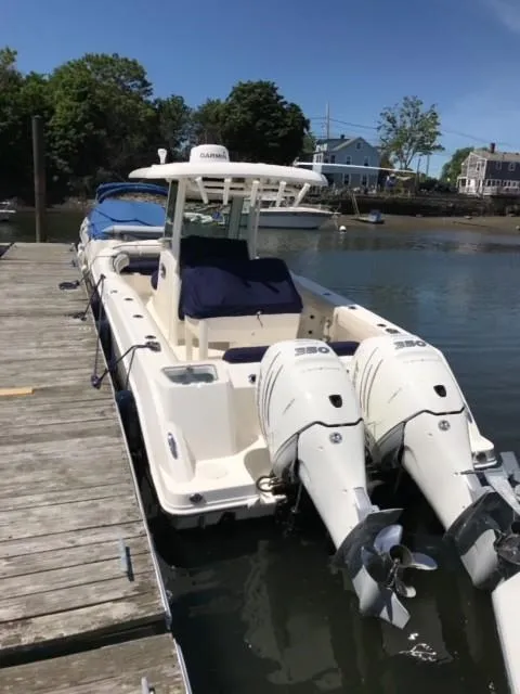 Slide: The Image of 2017 Boston Whaler 280 Outrage docked, featuring dual outboard engines, in a serene marina setting. - 2