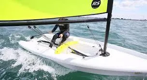 Slide: The Image of 2023 RS Zest sailboat navigating on open water with vibrant yellow sail. - 2