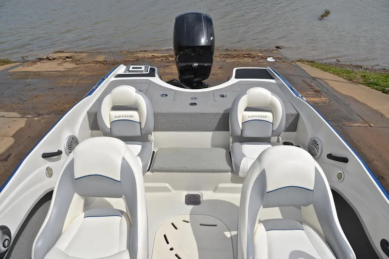 Slide: The Image of 2016 Nitro Z-7 Sport boat interior with four white seats, docked by the water. - 24