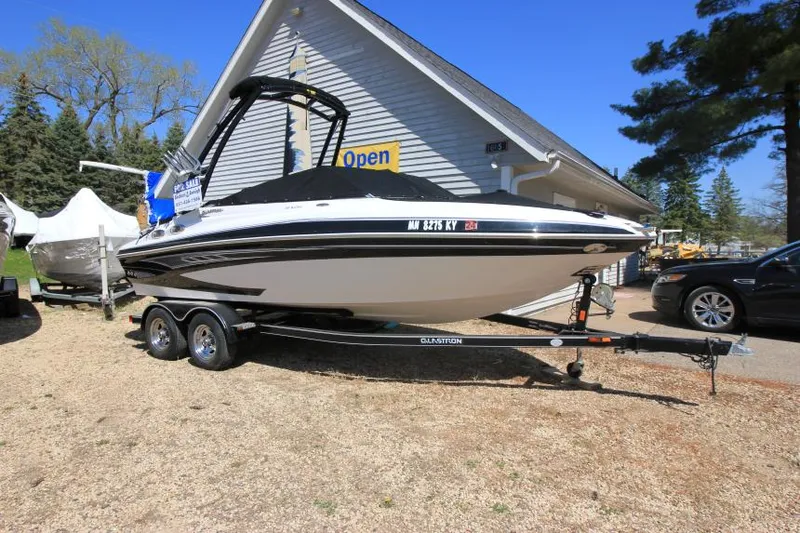 Slide: The Image of 2011 Glastron GLS 215 boat on trailer, parked outside a building with open sign. - 4