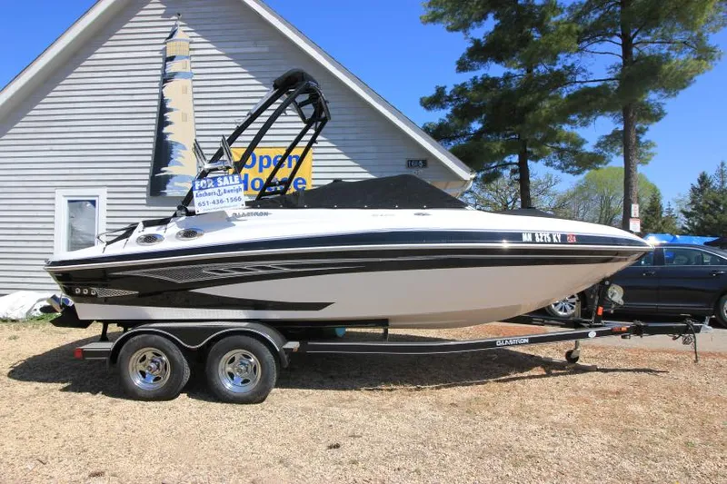 Slide: The Image of 2011 Glastron GLS 215 boat on trailer, parked outdoors near a building. - 5