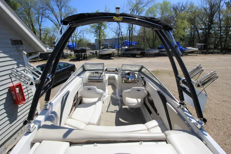 Slide: The Image of 2011 Glastron GLS 215 boat interior with seating and steering wheel, parked outdoors. - 8