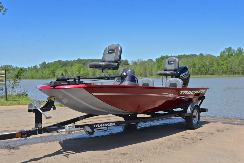 Slide: The Image of 2019 Bass Tracker Pro 170 boat on trailer by a lake, under clear blue sky. - 10