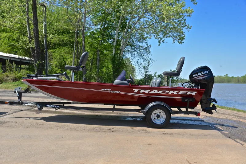 Slide: The Image of 2019 Bass Tracker Pro 170 boat on trailer by a lake, surrounded by trees. - 11