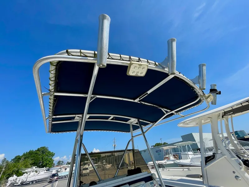 Slide: The Image of Seastrike 240 boat (2002) with blue canopy and rod holders under clear blue sky. - 15