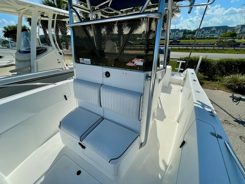 Slide: The Image of 2002 Seastrike 240 boat interior with cushioned seating and console, docked under clear skies. - 8