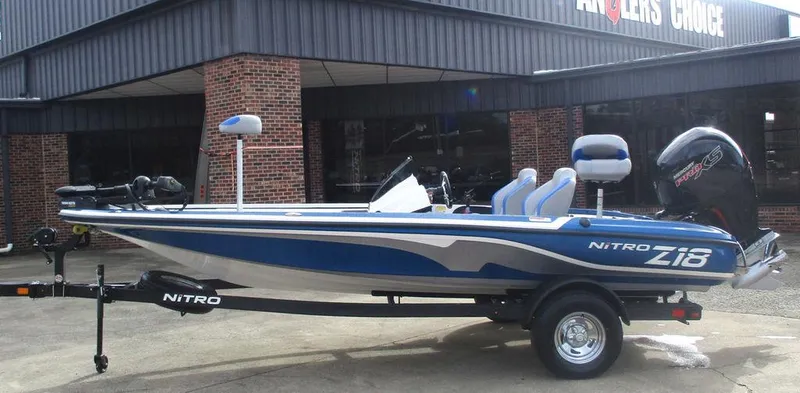 The Image of 2025 Nitro Z18 boat with blue and white design, parked on a trailer outside a building. - 1
