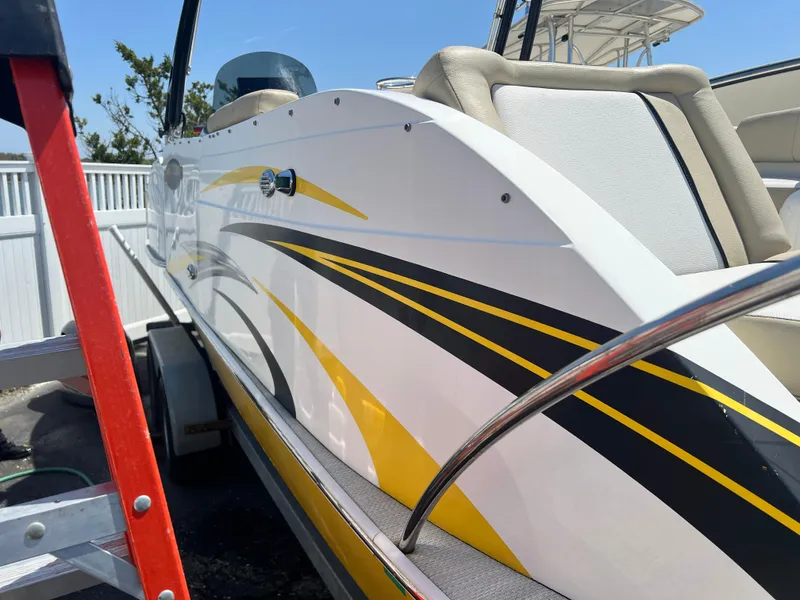 Slide: The Image of 2016 Caravelle RAZOR 238PR boat with sleek yellow and black graphics, docked outdoors. - 6