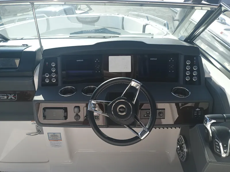 Slide: The Image of 2024 Chaparral 280 OSX boat dashboard with steering wheel and control panels. - 11