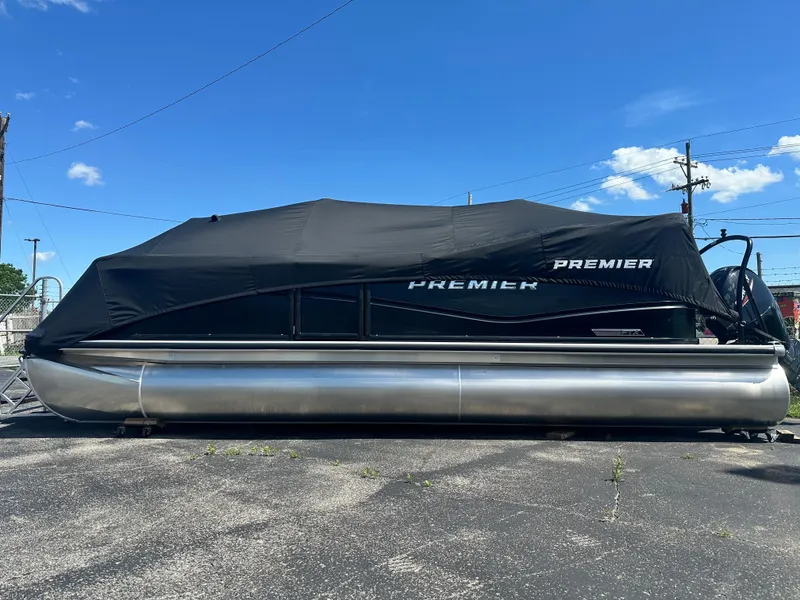 The Image of 2025 Premier 220 Sunscape RF pontoon boat covered, parked on asphalt under clear blue sky. - 1