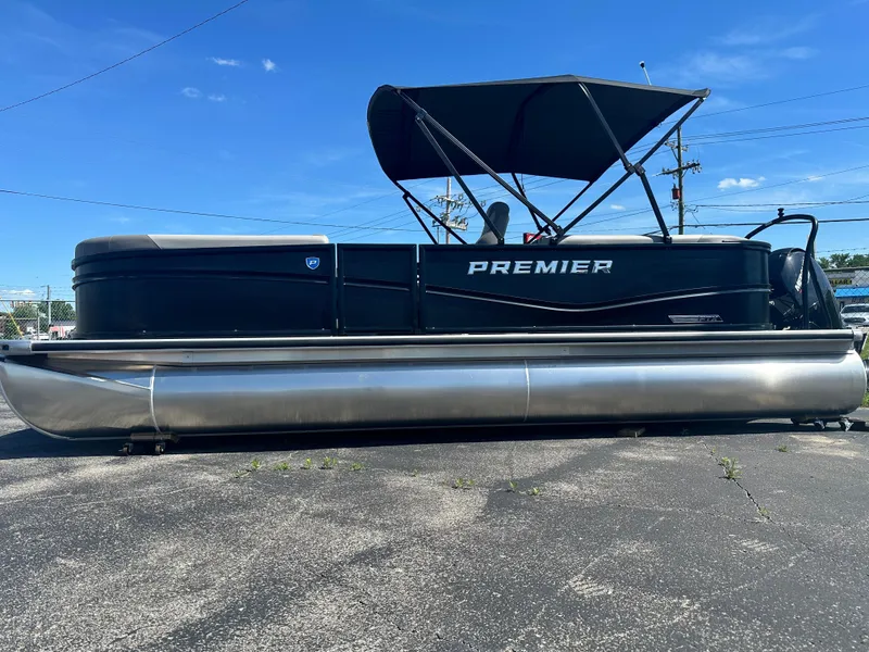 Slide: The Image of 2025 Premier 220 Sunscape RF pontoon boat with canopy, parked on pavement under clear blue sky. - 3