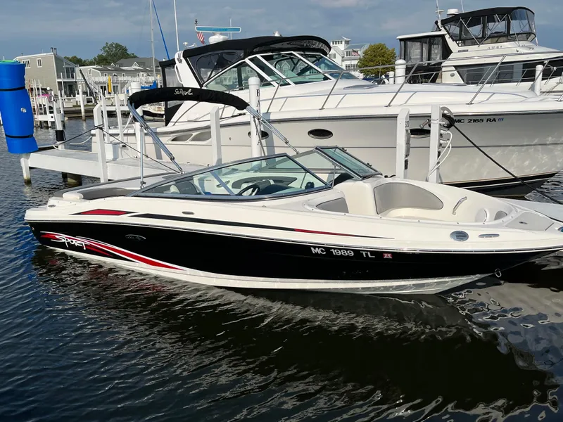 Slide: The Image of 2011 Sea Ray 205 Sport boat docked at marina, sleek black and white design. - 6
