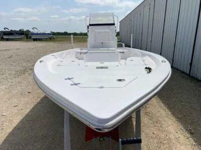 Slide: The Image of 2025 Blazer Bay 2220 Fisherman boat, white, parked outdoors near a metal building. - 2