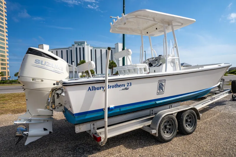 Slide: The Image of 2016 Albury Brothers 23 boat on trailer, featuring Suzuki outboard motor, parked outdoors. - 2