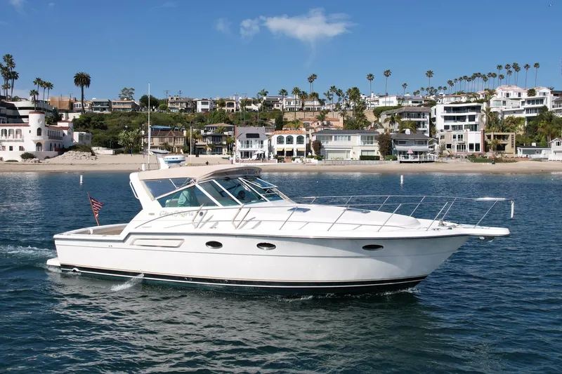 Slide: The Image of 1997 Tiara Yachts 3700 Open cruising near a scenic coastal neighborhood. - 9