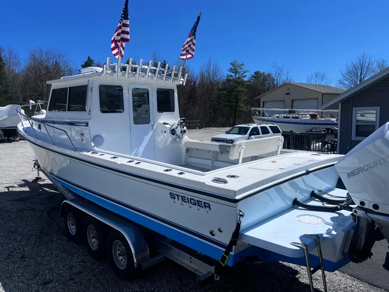 Slide: The Image of 2022 Steiger Craft 31 Chesapeake boat on trailer with American flags, parked outdoors. - 2