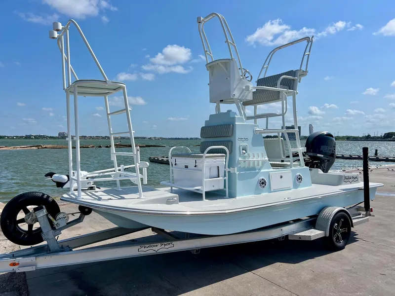 The Image of 2022 Shallow Sport 20 Classic boat on trailer by the water, clear sky background. - 1