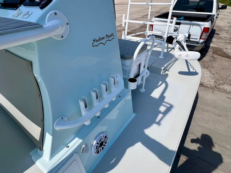 Slide: The Image of 2022 Shallow Sport 20 Classic boat with fishing rod holders and console, parked near a truck. - 15