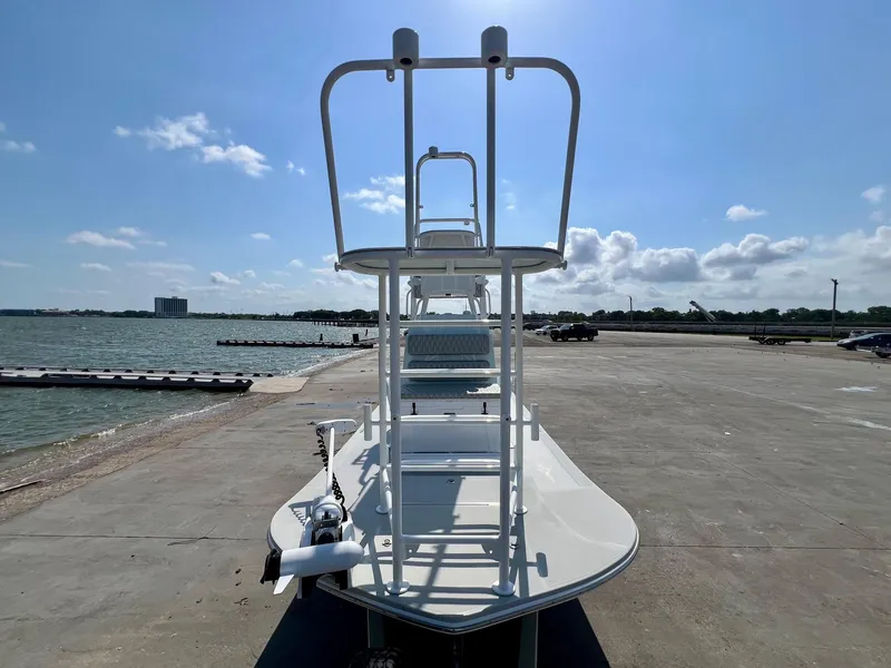 Slide: The Image of 2022 Shallow Sport 20 Classic boat docked by the waterfront under a clear blue sky. - 6