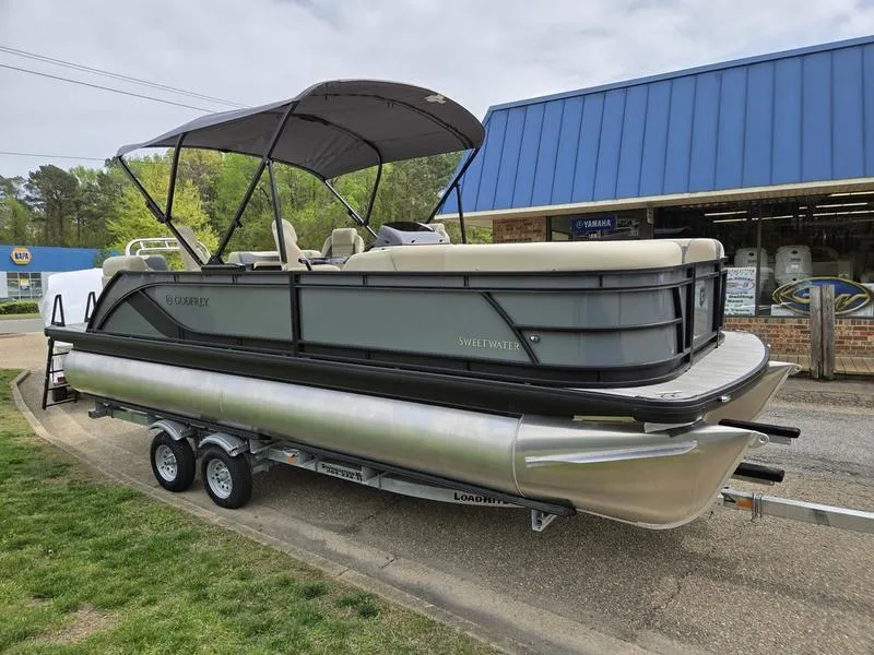 Slide: The Image of 2025 Godfrey Sweetwater 2286 QS pontoon boat on trailer, parked outside a building. - 13