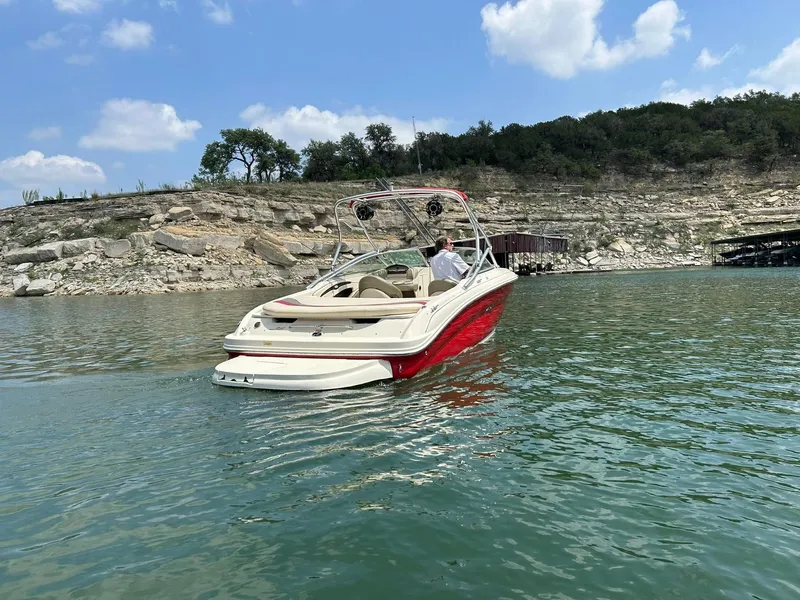 Slide: The Image of 2004 Sea Ray 240 Select boat on a lake with rocky shoreline and blue sky. - 16