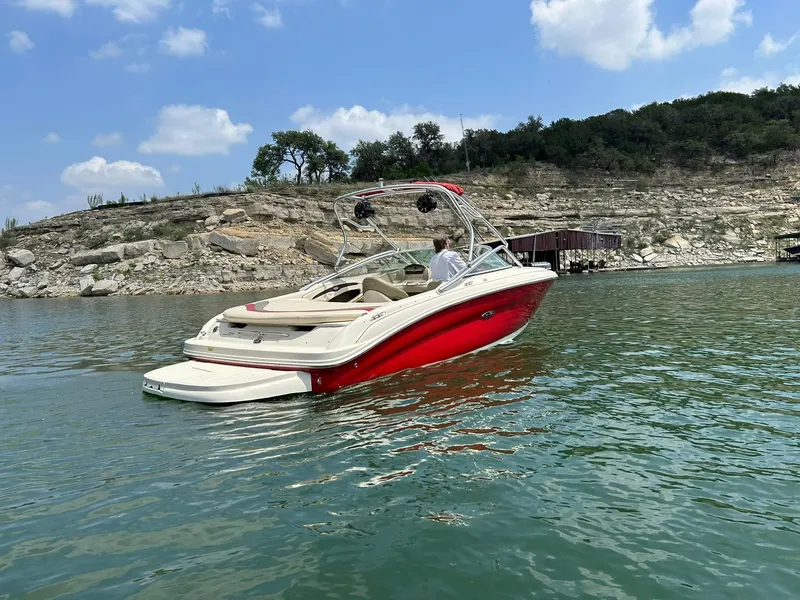 Slide: The Image of 2004 Sea Ray 240 Select boat on a lake with rocky shoreline and clear sky. - 17