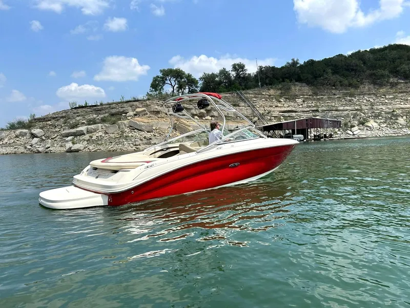 Slide: The Image of 2004 Sea Ray 240 Select boat on a lake with rocky shoreline and blue sky. - 18