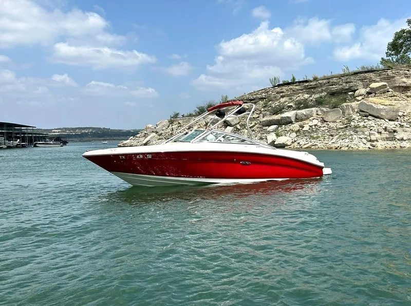 Slide: The Image of Red 2004 Sea Ray 240 Select boat on a lake with rocky shoreline background. - 2