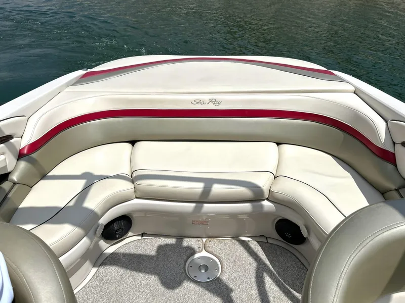 Slide: The Image of 2004 Sea Ray 240 Select boat interior with beige and red seating, on calm water. - 22