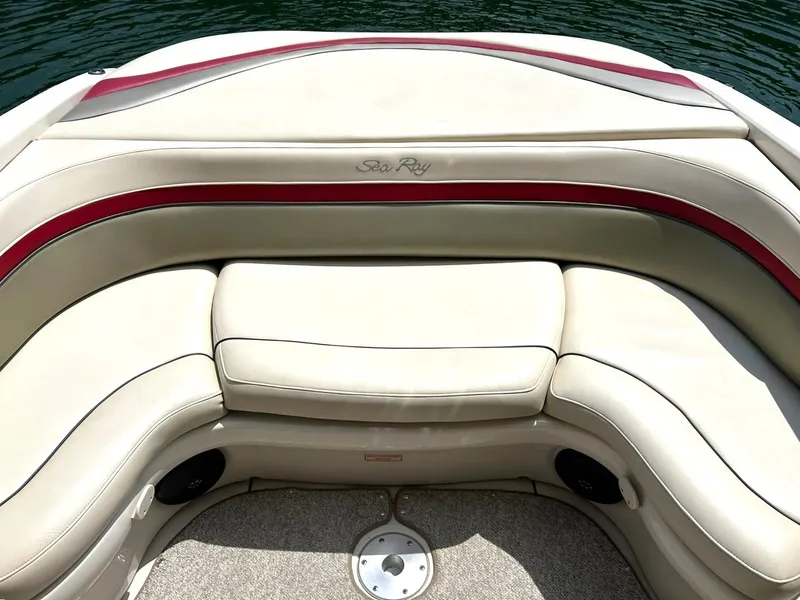 Slide: The Image of 2004 Sea Ray 240 Select boat interior with beige and red seating, on calm water. - 23