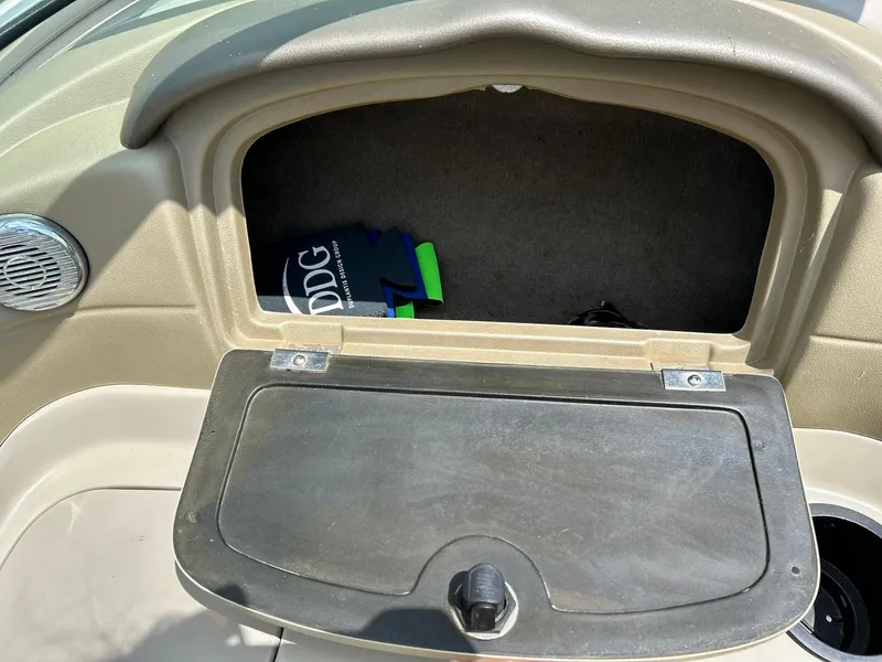 Slide: The Image of Open glove compartment in a 2004 Sea Ray 240 Select boat, showing interior storage space. - 27