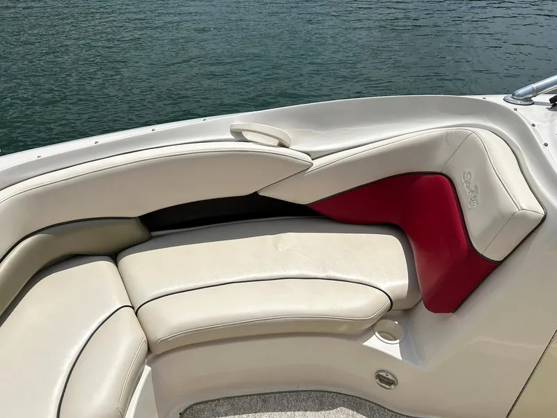 Slide: The Image of 2004 Sea Ray 240 Select boat interior with cream and red seating by the water. - 40