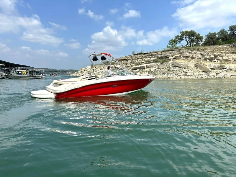 Slide: The Image of 2004 Sea Ray 240 Select boat on calm water, clear sky, rocky shoreline background. - 7