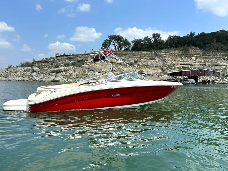 Slide: The Image of 2004 Sea Ray 240 Select boat on a lake with rocky shoreline and blue sky. - 8
