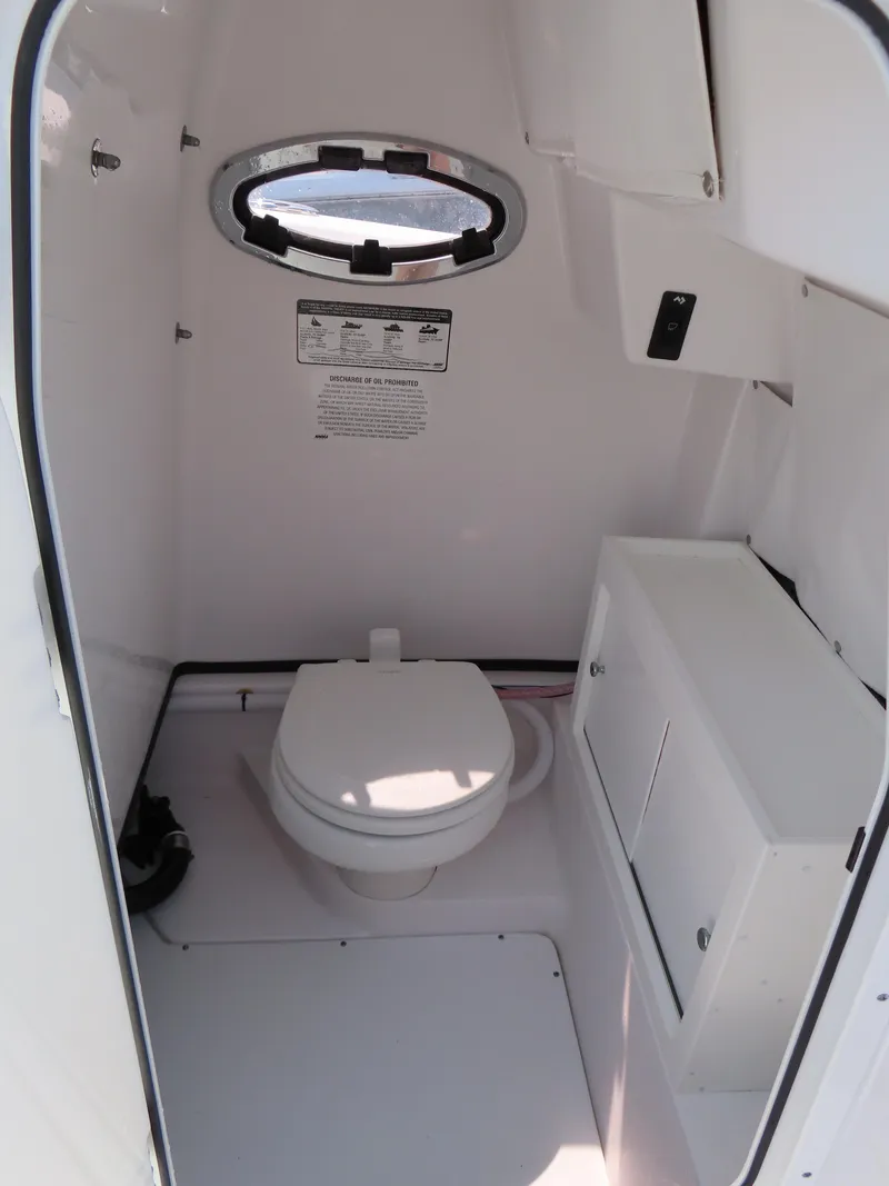 Slide: The Image of 2021 Sportsman Open 282 Center Console boat interior with toilet and storage. - 24
